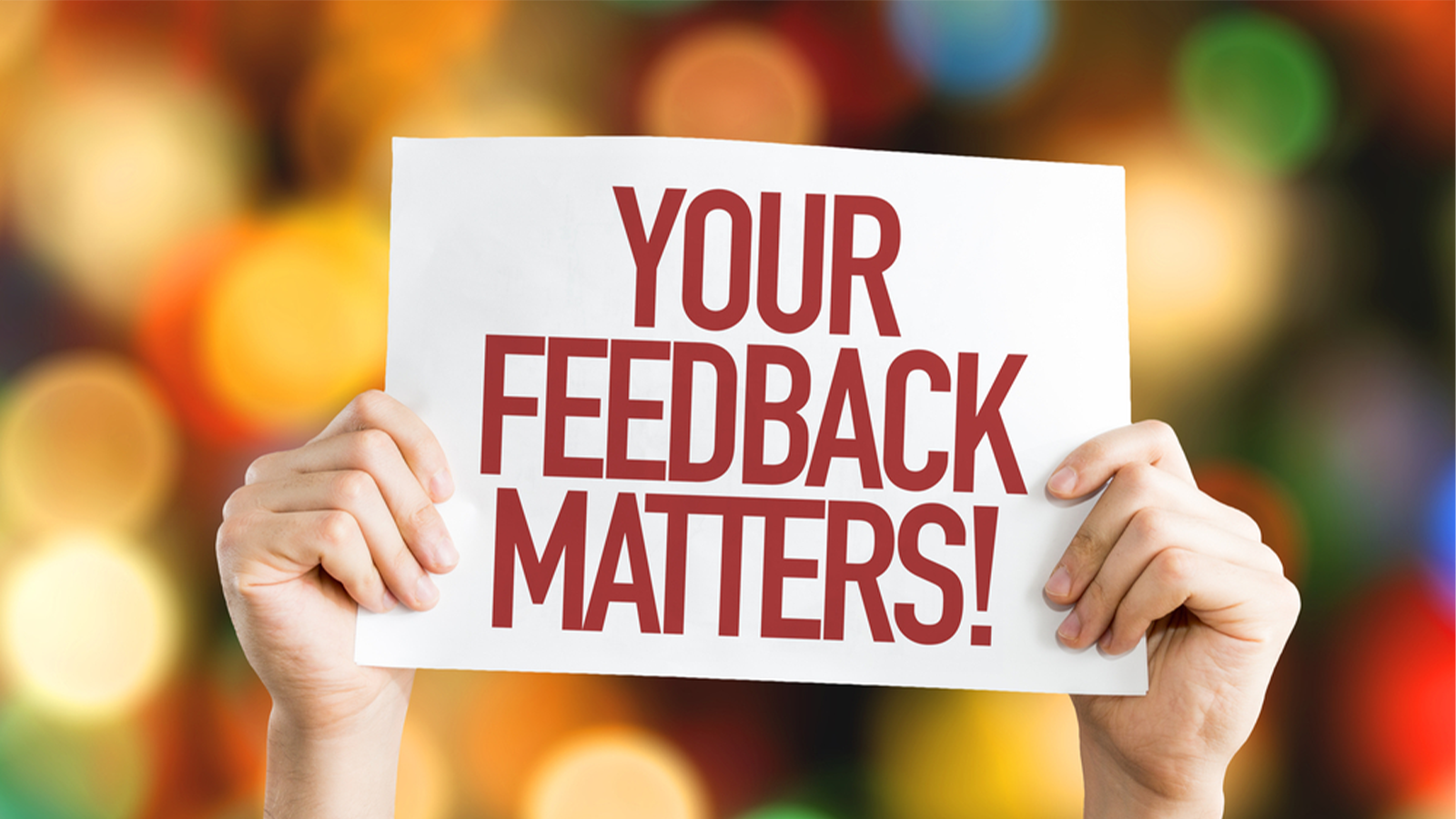 person holding sign that says your feedback matters